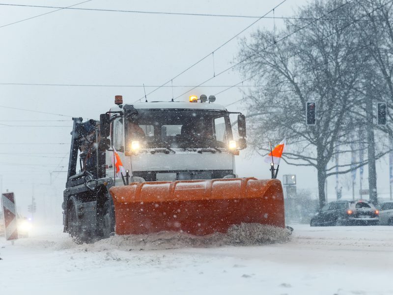 Plow truck pushing fresh snow off the road during a storm